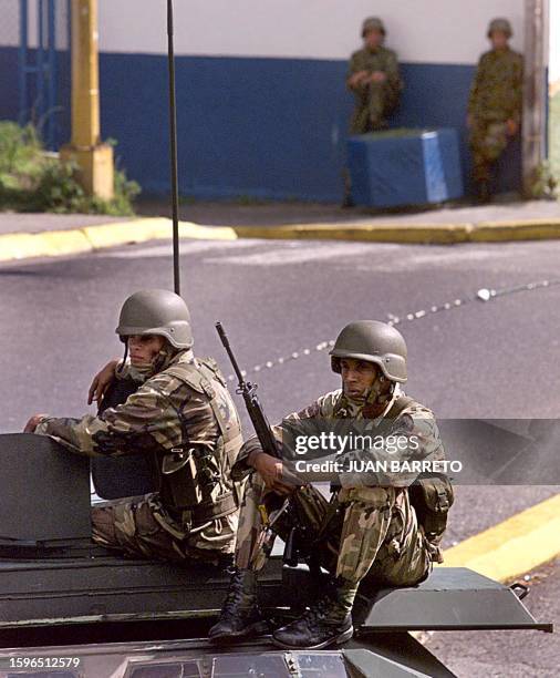 Members of the Venezuelan army seated on an armoured car guard the headquarters of the Metropolitan Police in Caracas 17 November 2002. The President...