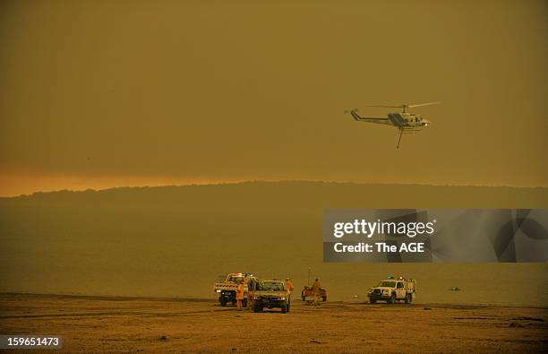 Firefighters and water bombing helicopters fill up at Lake Glenmaggiein the large rural region of Gippsland January 18, 2013 near Glenmaggie,...