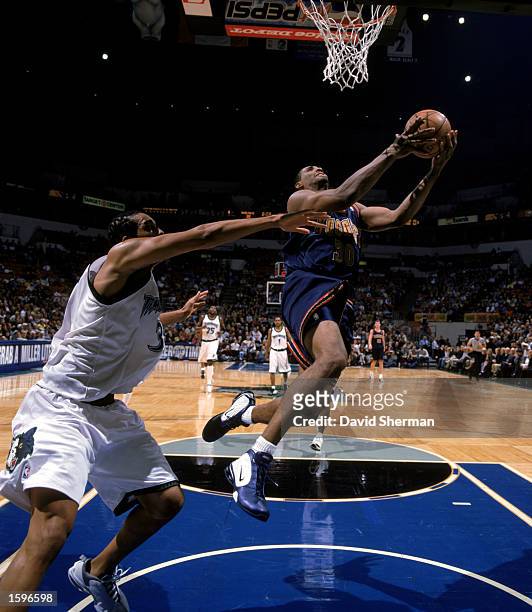 Mark Blount of the Denver Nuggets gets possession under the basket against the defense of Loren Woods of the Minnesota Timberwolves during the NBA...