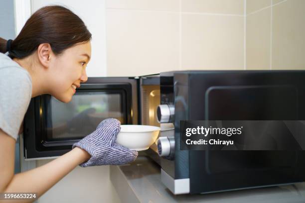 woman using microwave oven. - microwave dish stock pictures, royalty-free photos & images