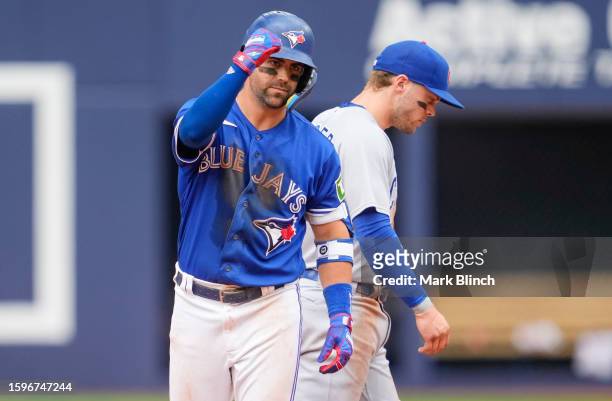 Whit Merrifield of the Toronto Blue Jays celebrates his RBI double in front of Nico Hoerner of the Chicago Cubs during the eighth inning in their MLB...