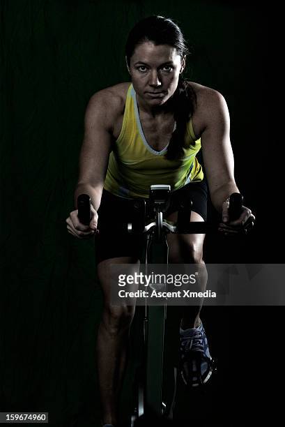 woman trains on stationary bucycle, in gym - heimtrainer stock-fotos und bilder