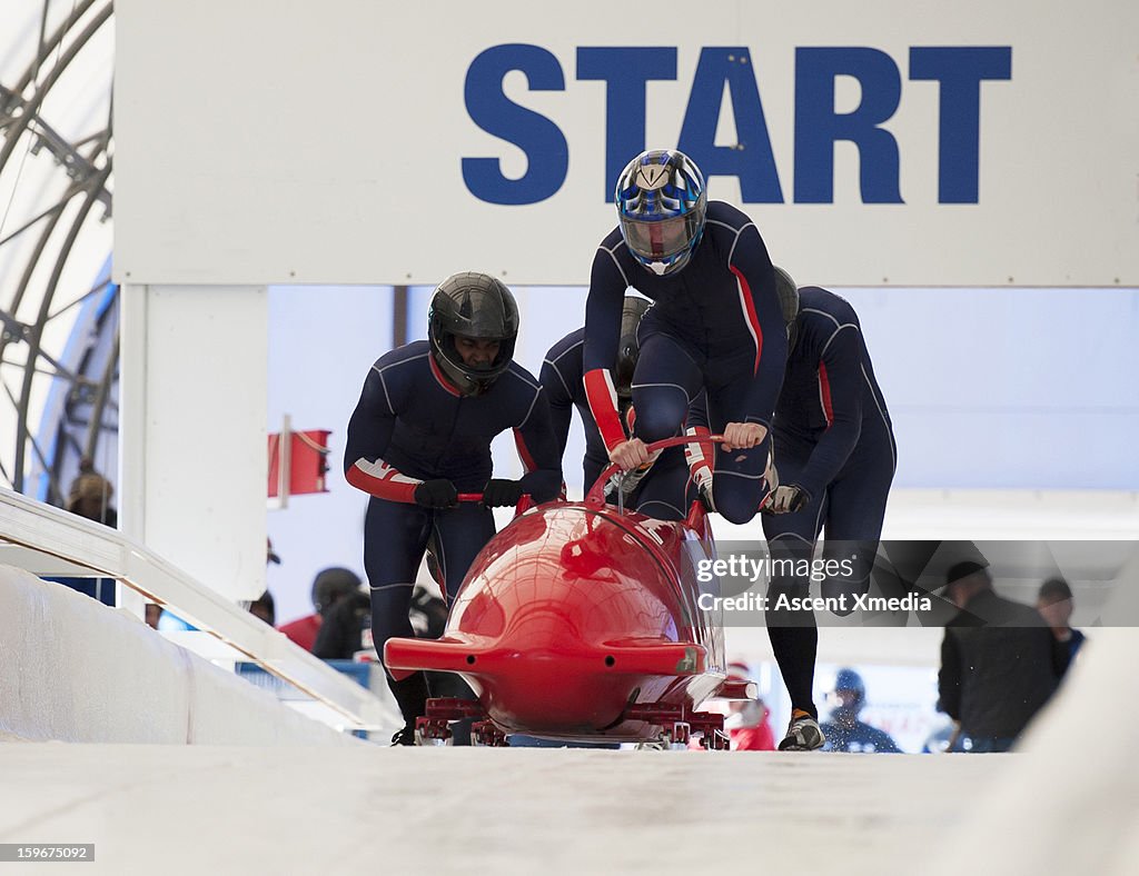 Team of bobsledders push bobsled out of start gate