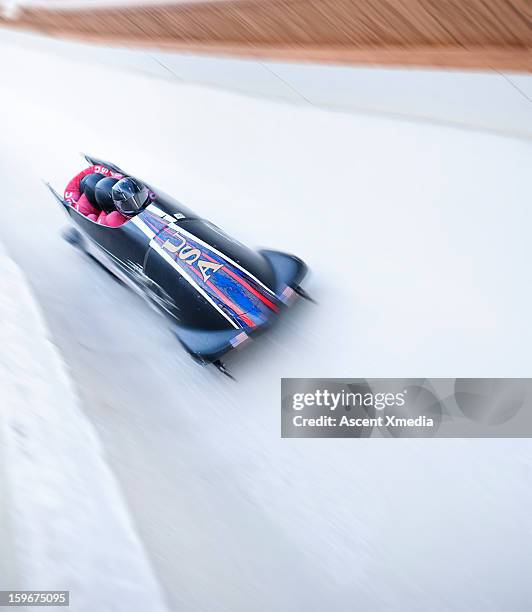 bobsled descends track with speed, motion blur - bobsleigh team stock-fotos und bilder