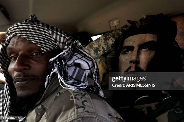 Libyan rebel sits in his vehicle next to an image of Argentine-born Cuban revolutionary leader Ernesto "Che" Guevara, on the outskirts of the town of...