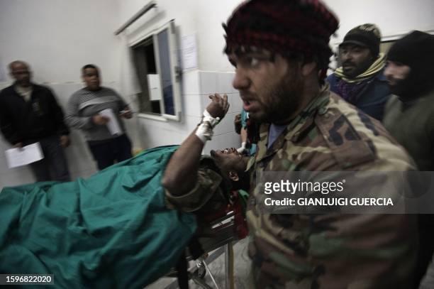 Libyan rebel fighter, wounded during heavy clashes with Kadhafi loyalists forces on the outskirt of the oil port of Ras Lanuf, is rushed to...
