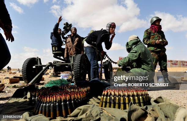 Libyan rebel fighters opposing Libyan strongman Moamer Kadhafi load ammunition into an anti-aircraft machine-gun as Libyan airforce fighter jets fly...