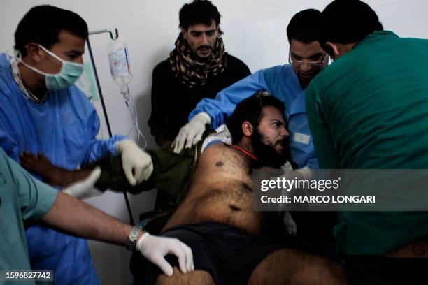 Wounded fighter is brought into a the Ras Lanuf Hospital from the battle in Bin Jawad on March 6 as tanks shell the centre of rebel-held Misrata, a...