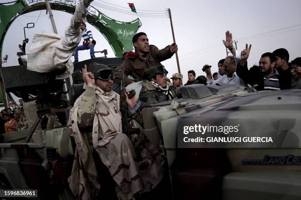 Libyan rebel fighters celebrate as they pass through Ajdabiya's west gate, 160 kms west of Benghazi, on their way to Ras Lanuf where heavy fighting...