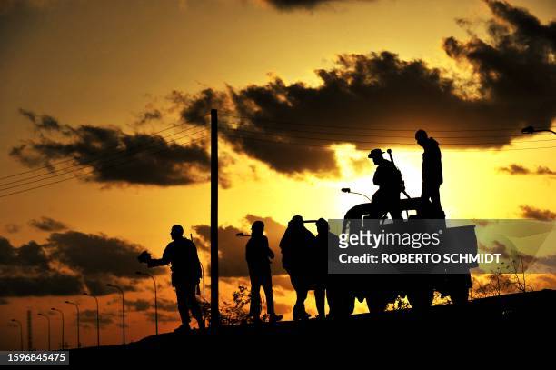 Libyan rebel fighters are silhouetted at sunset on March 7, 2011 in the oil centre of Brega as opposition forces ceded ground to Moamer Kadhafi's...