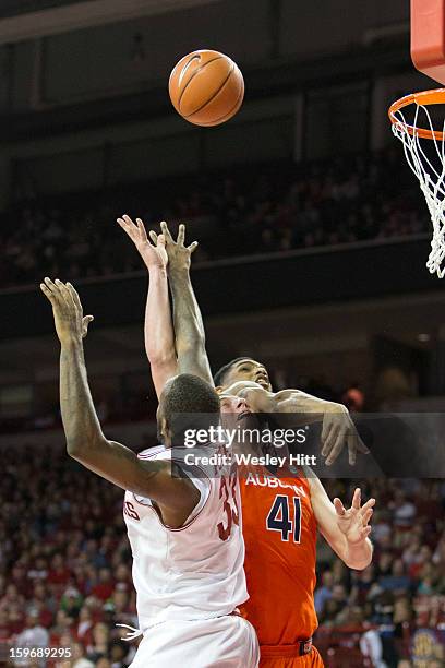 Rob Chubb of the Auburn Tigers is fouled by while taking a shot over Marshawn Powell and Coty Clarke of the Arkansas Razorbacks at Bud Walton Arena...