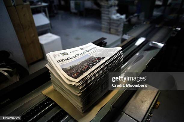 Newly-printed editions of the International Herald Tribune newspaper sit stacked for packaging on a conveyor belt at the Kathimerini printing plant...