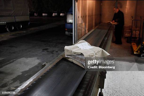 Worker prepares packaged bundles of the International Herald Tribune in the distribution area of the Kathimerini printing plant in Paiania, Greece,...