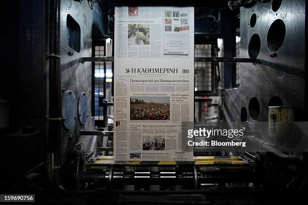 Newly-printed pages of the Kathimerini newspaper pass along the automated presses at the Kathimerini printing plant in Paiania, Greece, on Thursday,...