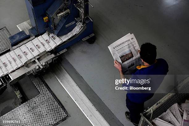 Worker inspects a newly-printed edition of the Kathimerini newspaper near the automated production line at the Kathimerini printing plant in Paiania,...