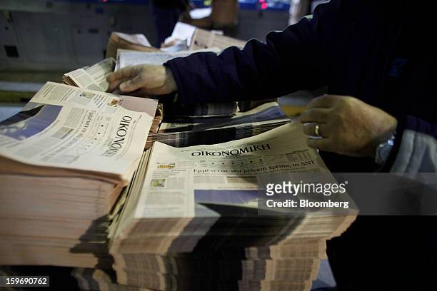Worker arranges newly-printed financial sections of the Kathimerini newspaper at the Kathimerini printing plant in Paiania, Greece, on Thursday, Jan....