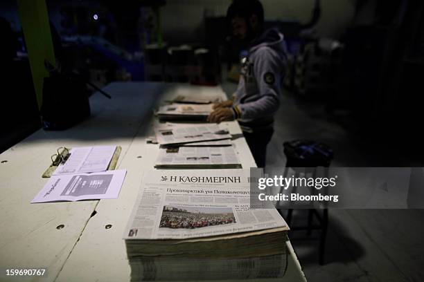 Worker inspects newly-printed copies of the Kathimerini newspaper at the Kathimerini printing plant in Paiania, Greece, on Thursday, Jan. 17, 2013....