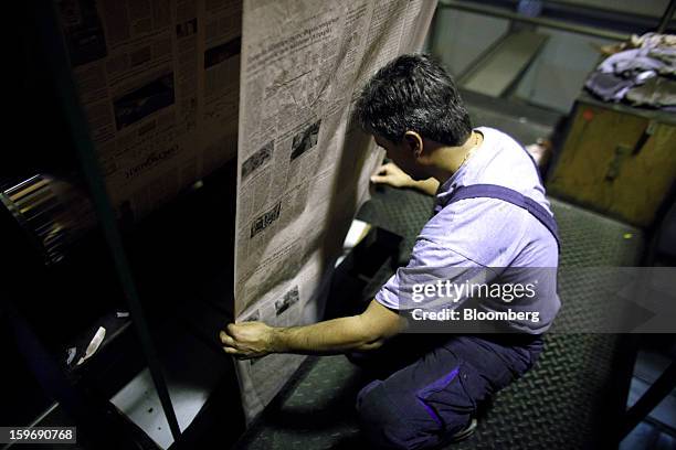 Worker positions a roll of newsprint during printing of the Kathimerini newspaper at the Kathimerini printing plant in Paiania, Greece, on Thursday,...
