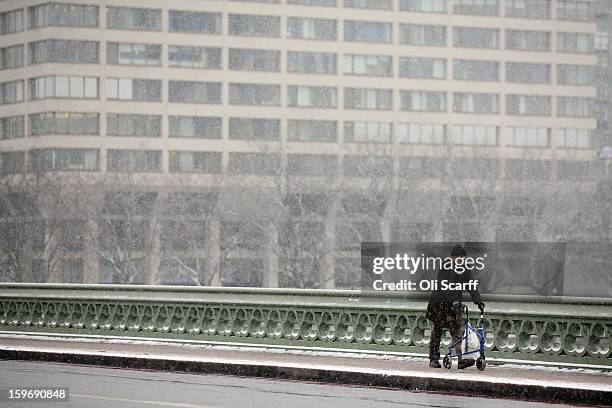 Man walks across Westminster Bridge as snow falls on January 18, 2013 in London, England. Widespread snowfall is affecting most of the UK with school...