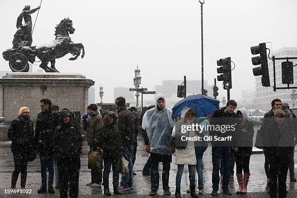 Members of the public wait to cross the road at the end of Westminster Bridge as snow falls on January 18, 2013 in London, England. Widespread...