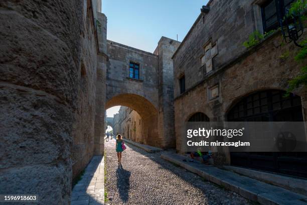 people walking down the street of knights (ippoton) in city of rhodes, rhodes dodecanese island, greece. famous tourist destination for summer holiday in south europe. - rhodes old town stock pictures, royalty-free photos & images