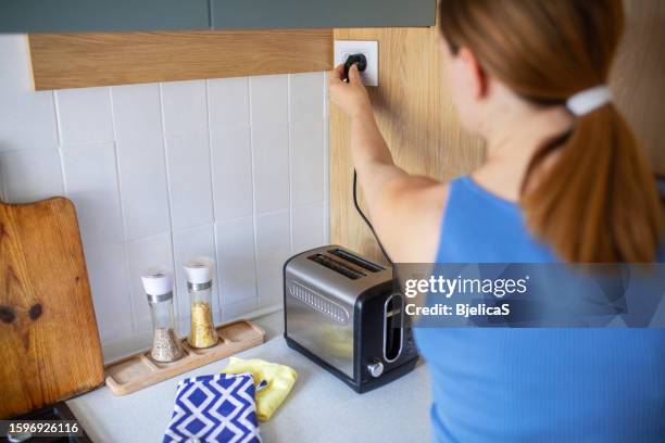 woman using toaster to make breakfast in kitchen at home - electrical plug stock pictures, royalty-free photos & images