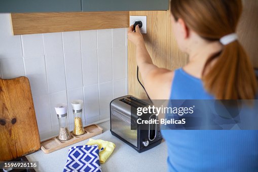 Woman using toaster to make breakfast in kitchen at home Woman using toaster to make breakfast in kitchen at home