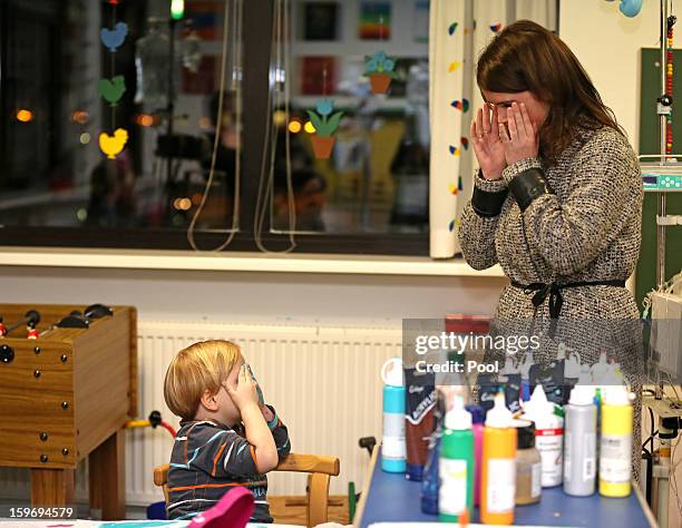 Princess Eugenie plays peek-a-boo with a young patient during a visit to the Teenage Cancer Treatment Unit at the University of Medicine on January...