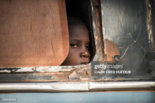 Malian girl looks out from a bus as Malian army soldiers prepare to check the vehicule and passengers at a checkpoint in the city of Niono, on...