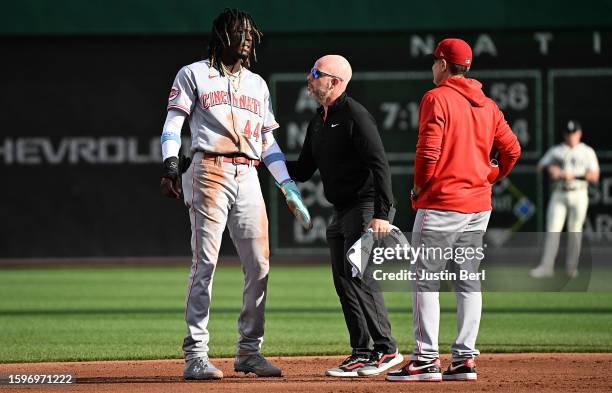 Elly De La Cruz of the Cincinnati Reds is looked at by trainer Sean McQueeney and manager David Bell after an apparent injury in the first inning...