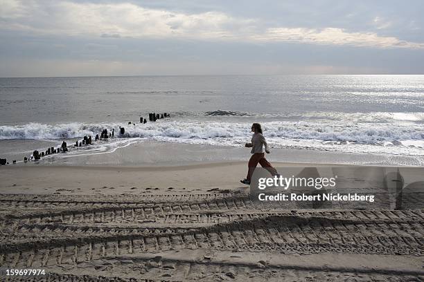 Woman jogs along the beach January 17, 2013 where a boardwalk had been removed after being damaged during Hurricane Sandy in the Rockaways January...