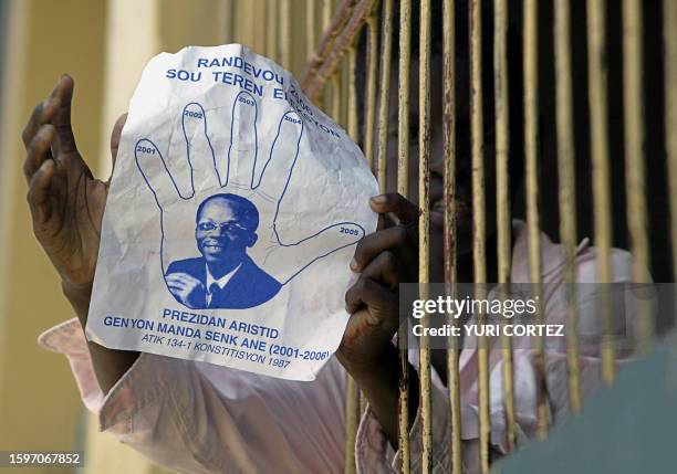 Sympathizer of former Haitian President Jean Bertrand Aristide shows a flyer with the photo of Aristide after a march in the Bel Air district of...