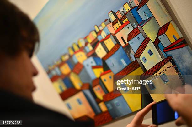 Visitor looks at a painting by Italian artist and former killer and drug trafficker for the Cosa Nostra mafia, Gaspare Mutolo, during the opening of...