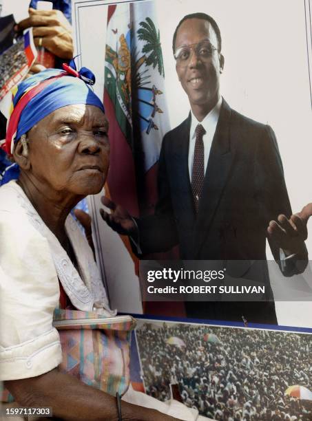 An elderly supporter of Haitian President Jean Bertrand Aristide holds a poster 16 December 2003, while listening to his speech at a university...