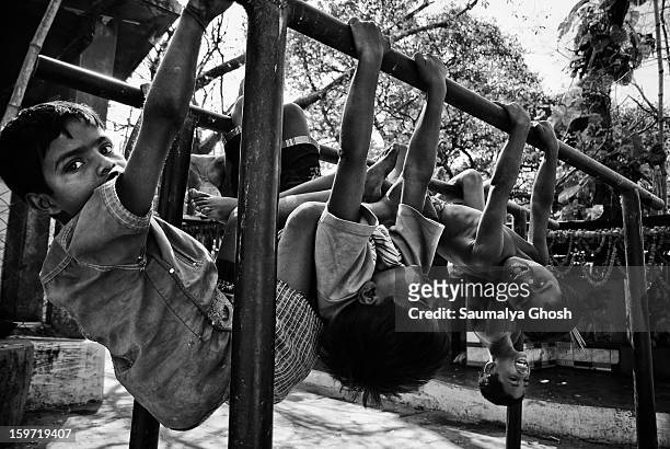 On the streets of Kolkata, a few boys are hanging on the iron bars and enjoying themselves.