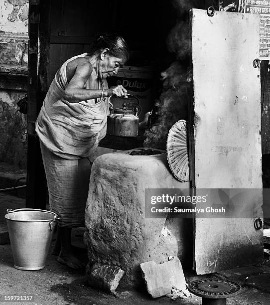 On the streets of Kolkata, an old woman, a roadside shop owner, is preparing early morning tea for the customers.