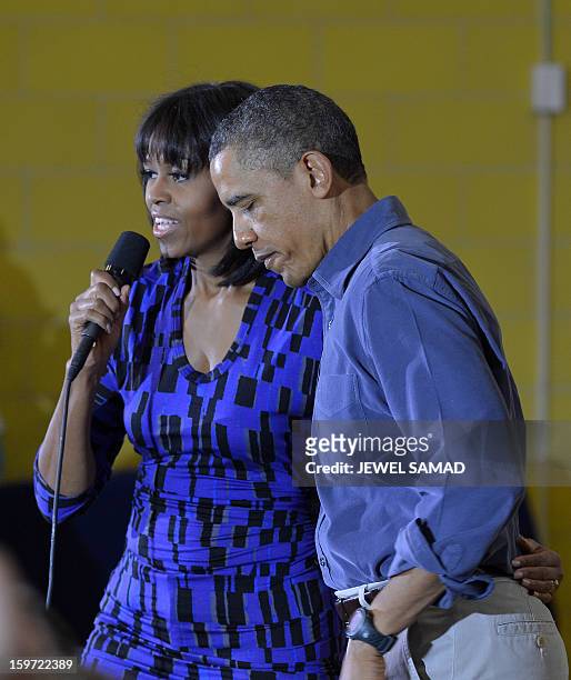 President Barack Obama listens as First Lady Michelle Obama speaks to a crowd at Burrville Elementary School after participating in National Day of...