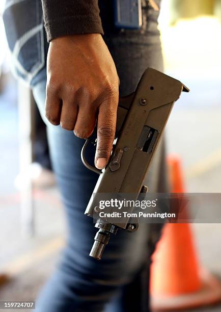 An unidentified woman waits in line with a MAC-9 semi-automatic pistol at a gun buy back program at the First Presbyterian Church of Dallas on...