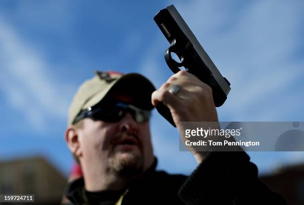 Second Amendment supporter and gun enthusiast Derek Ringley displays an unloaded pistol that was being sold in an impromptu auction across the street...