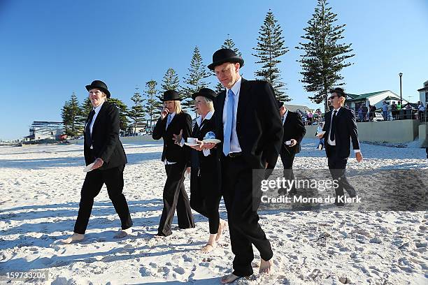 Participants walk onto the beach dressed in suits and bowler hats as part of an art installation created by surrealist artist Andrew Baines on...