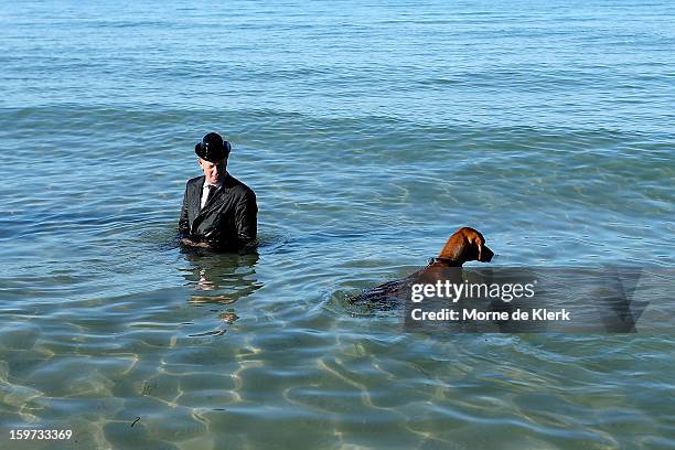 Man wearing a suit and bowler hat stands in the water after taking part in an art installation created by surrealist artist Andrew Baines on January...