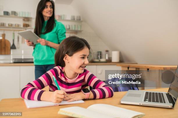mother assisting her daughter while she's doing homework - workbook stock pictures, royalty-free photos & images
