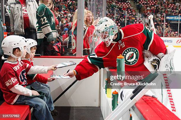 Josh Harding of the Minnesota Wild signs autographs for two lucky fans prior to the game against the Colorado Avalanche on January 19, 2013 at the...