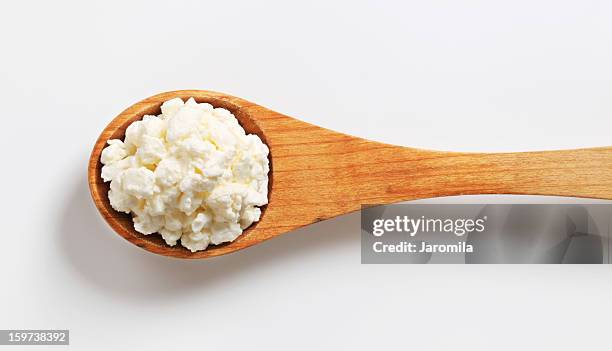 hüttenkäse auf einem hölzernen löffel - hüttenkäse stock-fotos und bilder
