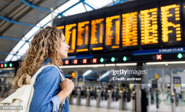traveler at the airport looking at the arrival departure board - seguro de viagem imagens e fotografias de stock