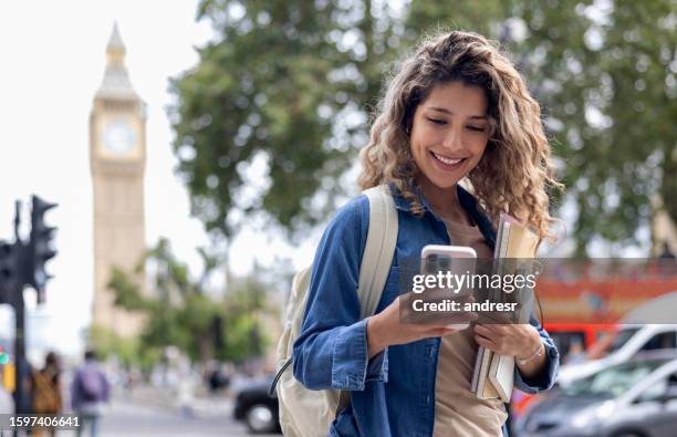 exchange student using her cell phone while walking around london - student visa stockfoto's en -beelden