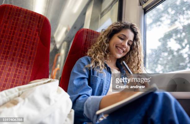 commuter riding on a train and writing on her notepad - london train stock pictures, royalty-free photos & images