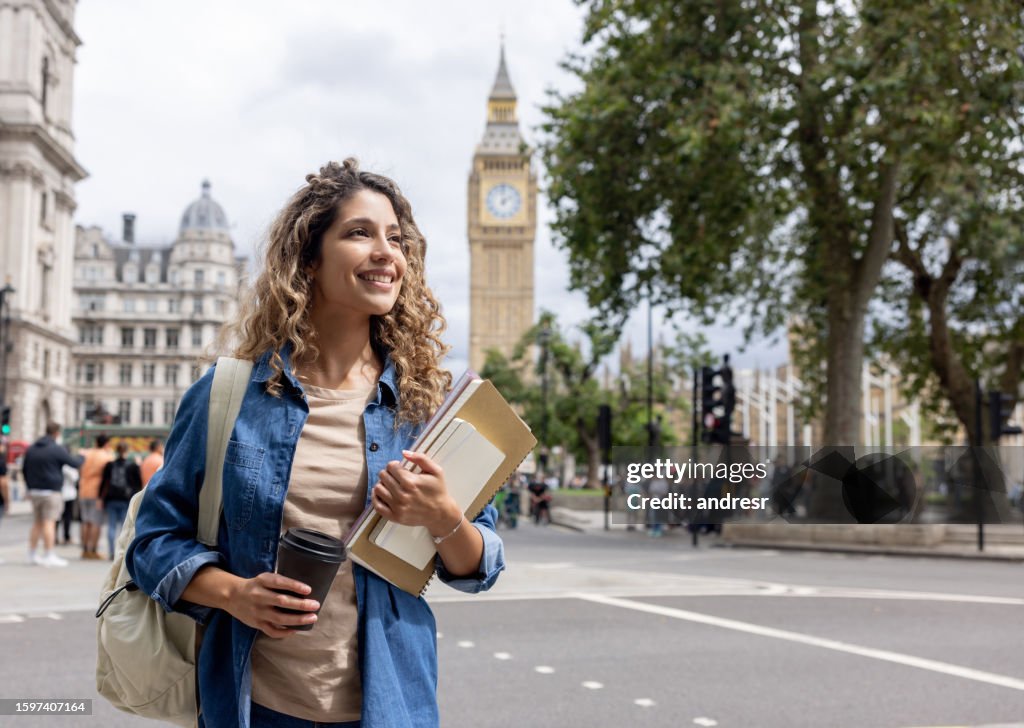 Exchange student walking outdoors in London and drinking coffee