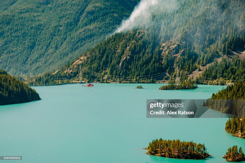 A helicopter over a Diablo lake while fighting a forest fire