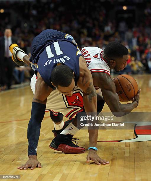 Mike Conley of the Memphis Grizzles falls over Nate Robinson of the Chicago Bulls at the United Center on January 19, 2013 in Chicago, Illinois. The...